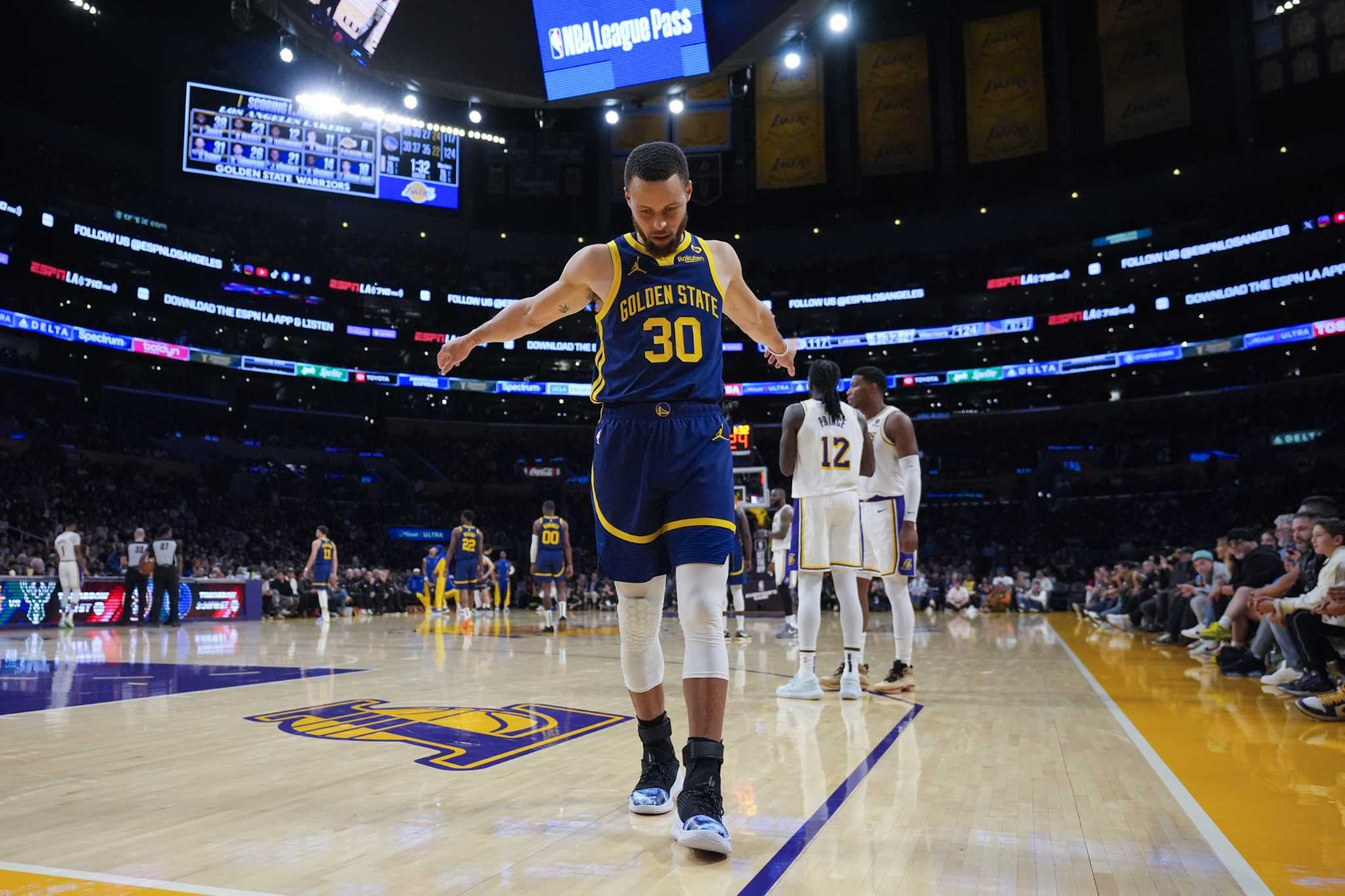 Stephen Curry assists LeBron James with an alley-oop slam during a fast break.